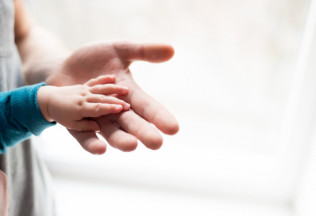 Child’s hand on adult’s palm symbolizing trust and support — NRIWAY Birth Certificate Attestation Services.