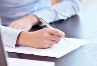 Person signing official papers – representing the start of NRI birth certificate attestation.