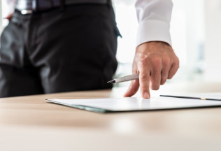 Professional pointing at a document on a desk with a pen – NRIWAY company services.
