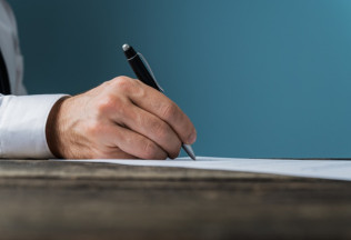 Hand signing a document for birth certificate attestation – NRIWAY company services.