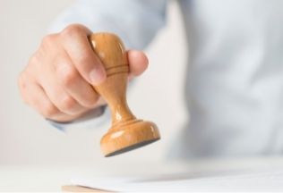 Hand stamping a document – final approval step in NRI birth certificate attestation.